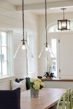 a dining room table with chairs and lights hanging from it's ceiling over it