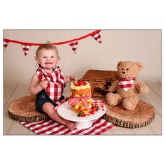 a baby sitting next to a cake and teddy bear