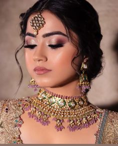 a woman in a bridal outfit with jewelry on her neck and shoulder, looking down at the camera