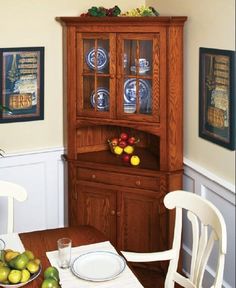 a wooden china cabinet sitting in the corner of a dining room next to a table