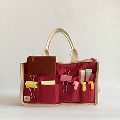 a red bag filled with lots of items on top of a white table next to a wall