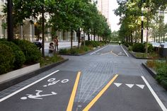 an empty city street with yellow arrows painted on the pavement and trees lining both sides