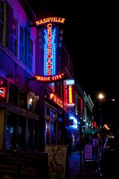 a city street at night lit up with neon signs