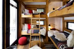 bunk beds in a room with wooden walls and flooring, along with other furniture