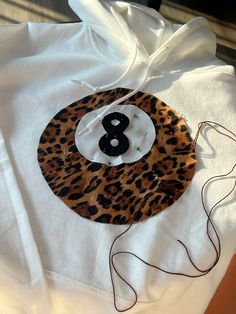 a white hoodie with an animal print number eight on it