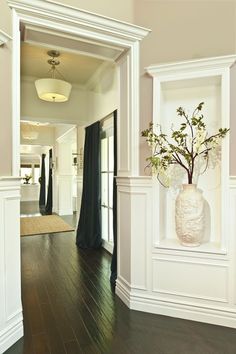 a vase with flowers in it is sitting on the wall next to an open doorway