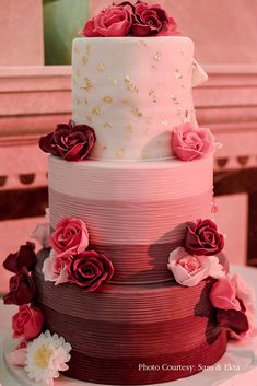 a three tiered cake with pink and red flowers on it