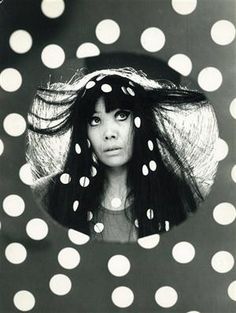 a black and white photo of a woman wearing a polka dot hat