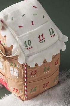 a gingerbread house made out of paper and fabric with numbers on the roof, including one number