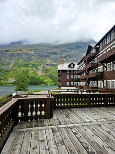 a wooden deck with railings and buildings in the background on a cloudy day,