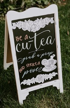 a chalkboard sign sitting in the grass with writing on it that says be a cut - tea