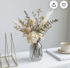 a vase filled with flowers sitting on top of a table next to a cup and saucer