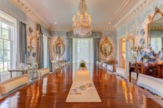 an elegant dining room with chandeliers and large wooden table in front of windows