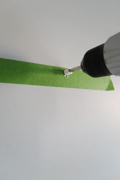 a green piece of paper being cut with a drill