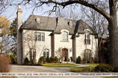 a large white brick house with lots of windows on it's roof and two chimneys