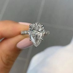 a woman's hand holding an engagement ring with two pear shaped diamonds