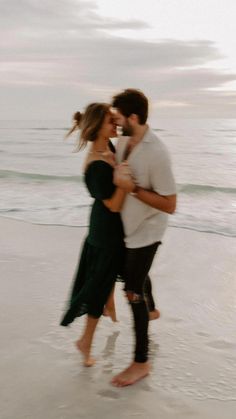 a man and woman are kissing on the beach while holding each other's hands