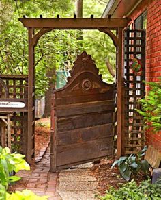 an old wooden bed sitting in the middle of a garden next to a brick building