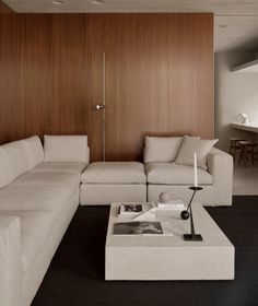 a living room with white couches and wooden paneling on the wall behind it