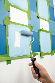 someone is painting the wall with blue and green squares on it while using a paint roller