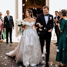 a bride and groom walking down the aisle with confetti thrown in the air