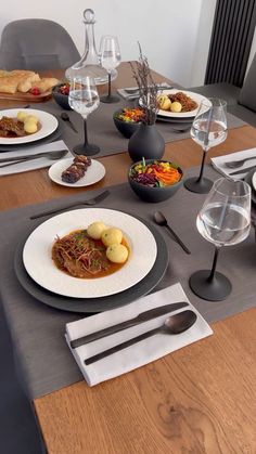 a dining table set with plates and silverware, utensils and wine glasses