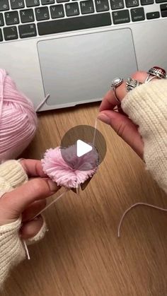 two hands are holding yarn and one has a ball of yarn in the other hand