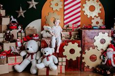 a young boy sitting on top of boxes with teddy bears in front of them and christmas decorations behind him