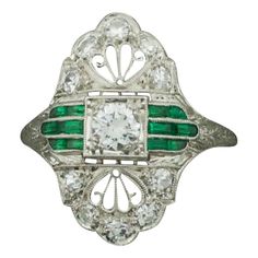 Art Deco 1920's Platinum Diamond Ring with Green Stones .55 carats One Round Brilliant Cut Diamond weighing .25 carats approximately [GH VVS-VS1] Ten Round Cut Diamonds weighing .30 carats approximately [GH VVS-VS1] Twelve Fancy Cut Green Stones. Glass or Better. Beautiful Filigree and Engraving. Ring Size 6 1/2 Green Cabochon Rings In Art Deco Style, Art Deco Multi-stone Emerald Ring For Anniversary, Luxury Art Deco Cabochon Rings, Art Deco Green Cabochon Rings, Art Deco Multi-stone Collectible Jewelry, Ring Stones, Platinum Diamond Ring, Art Deco 1920s, Green Stones