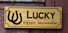 a wooden sign hanging from the side of a red building that says lucky owner, mackenzie