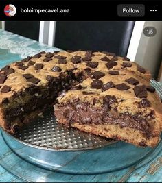 a chocolate chip cookie cake cut in half on a metal platter with one slice missing