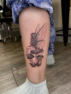 a woman's leg with a fairy on it and mushrooms in the foreground