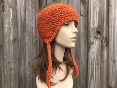 "Knit Hat Style: Garter Earflap Helmet - a chunky knit hat with ear flaps and knitted ties, for women, men and teens. Color: This sample hat is shown in Pumpkin. Sizes: One size fits average teen or adult head size of 20\" to 23\" (50.5 cm to 58 cm). Fiber Content: 80% acrylic, 20% wool Characteristics: Whimsical, chunky, very soft, warm and cozy. Care Instructions: Hand wash, dry flat. Every item from Pixiebell is handmade and knit or crocheted to order, unless otherwise stated in title of the Adjustable Knitted Bonnet For Outdoors, Knitted Beanie With Ear Flaps For Cold Weather, Cold Weather Knitted Beanie With Ear Flaps, Casual Knitted Hat With Ear Flaps, Adjustable Knitted Beanie With Ear Flaps, Knitted Adjustable Hats With Ear Flaps, Adjustable Knitted Hats With Ear Flaps, Knitted Adjustable Ear Flaps Hat, Cozy Adjustable Hand Knitted Crochet Hat