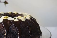 a bundt cake with chocolate icing and almonds on top is sitting on a plate