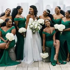 a group of women standing next to each other wearing green dresses and holding bouquets