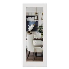 a dining room with white chairs and a painting on the wall behind it's door