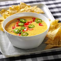 a white bowl filled with soup surrounded by tortilla chips and jalapenos