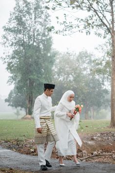 a man and woman dressed in traditional garb walking through the rain