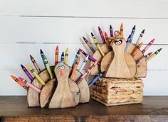 two wooden turkeys with colored crayons on them sitting next to each other