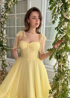 Step into the sunshine with this enchanting light yellow midi dress, perfect for any garden party or summer soirée. Its playful dotted pattern and off-shoulder neckline are beautifully adorned with delicate floral appliqués, adding a touch of romance. Alternatively, choose a charming bow strap design for a sweet, refined look. The dress features a supportive corset with built-in pads and boning, cinched at the waist to enhance your silhouette, and flows into a gathered hem for a touch of whimsy. Functional yet stylish, it boasts inseam pockets and a lace-up back closure, ensuring both comfort and a perfect fit. Ideal for those romantic occasions, this dress promises to be a delightful addition to your wardrobe. Night Clothes, Frocks And Gowns, Bow Straps, Prom Dresses Yellow, Yellow Midi Dress, Cute Prom Dresses, Yellow Polka Dot, Dress Yellow