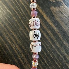 a hand holding a beaded necklace with words on it