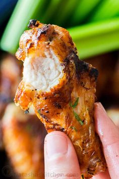 a hand holding up a piece of chicken