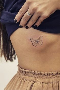 a woman's stomach with a small butterfly tattoo on her lower back and side