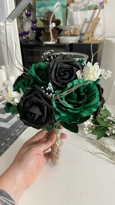 a person holding a bouquet of flowers on top of a white table in front of a mirror