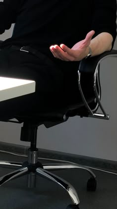 a person sitting in an office chair holding their hands together