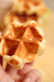 a person holding up a waffle shaped food item in their left hand, with the top half partially eaten