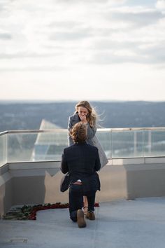 two people standing on top of a building talking on their cell phones while another person walks by