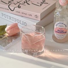 a bottle of gin and some books on a table with a glass filled with ice