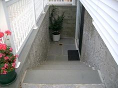 the stairs lead up to an apartment building with potted plants on each side and one door open