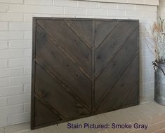 a large wooden door sitting next to a metal bucket filled with dried flowers and plants